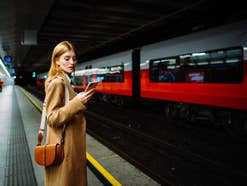 frau-am-bahnhof-mit-smartphone Frau am Bahnhof mit Smartphone