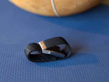 Ein Whoop MG Sensorarmband liegt auf einer blauen Oberfläche, mit einem Basketball, der teilweise im Hintergrund sichtbar ist.