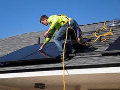 Solar-Rechner zeigt günstige Anbieter für Solar-Anlage Ein Handwerker montiert eine Solaranlage auf einem Dach